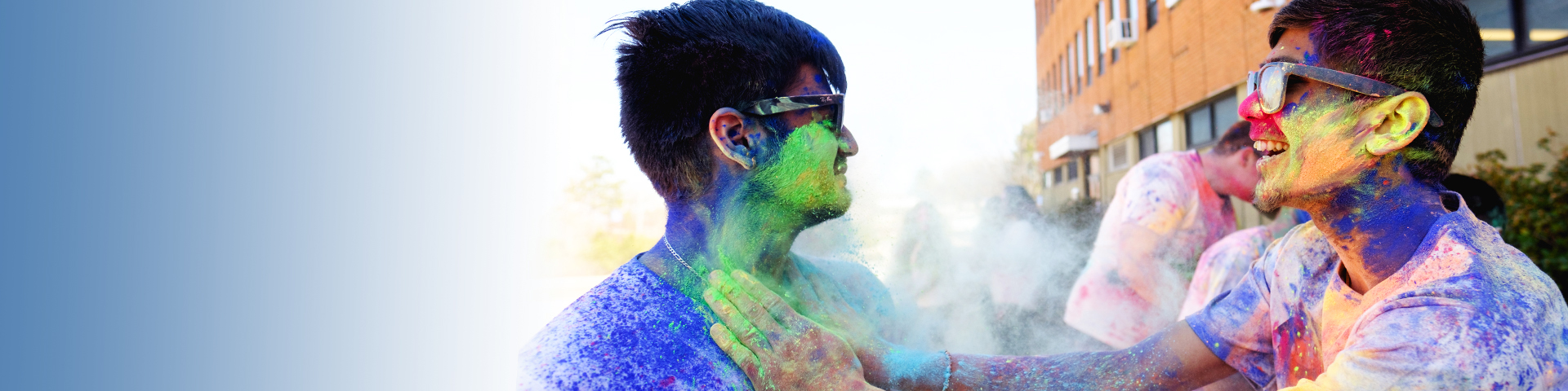 smiling students throw colorful paint on one another