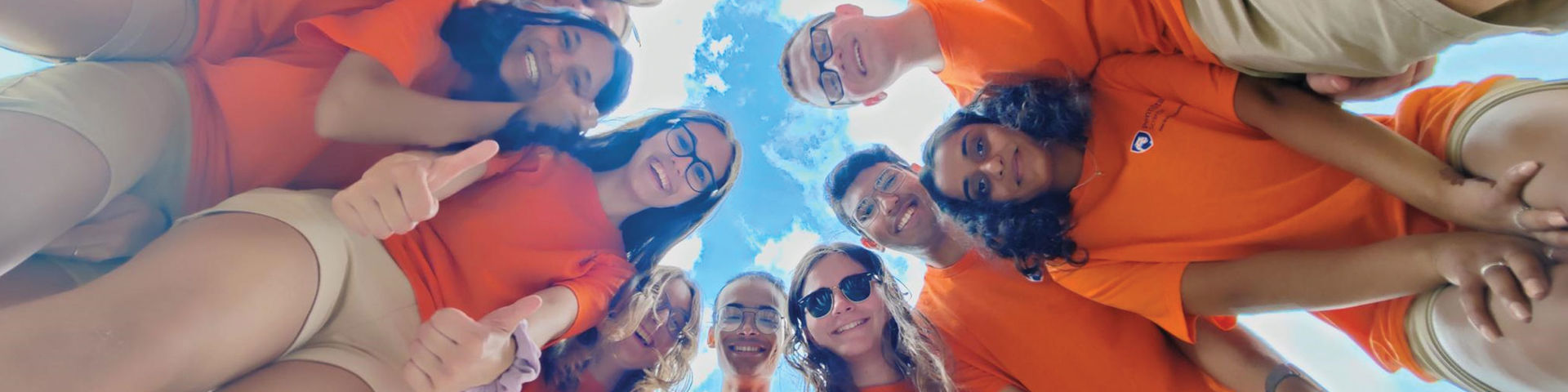 group of smiling student leaders in a circle photographed from below looking at photographer