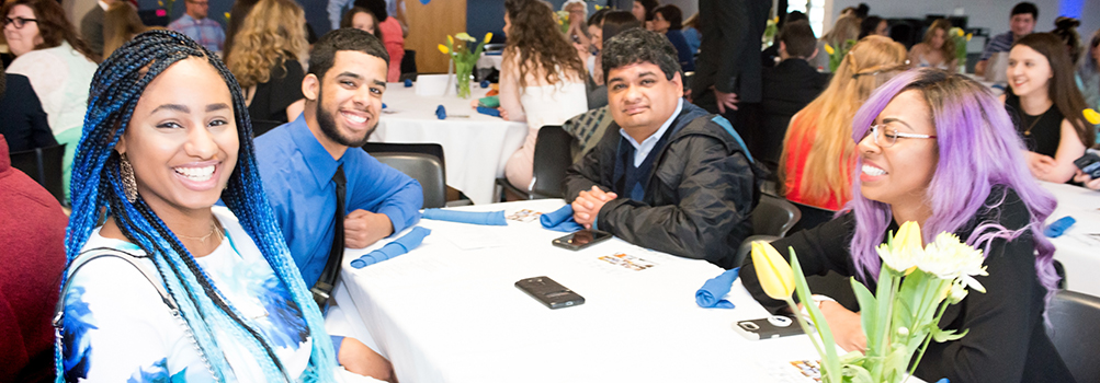 diverse group of smiling people at sitting at a table at a party or event