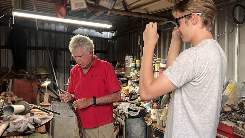 Erik Kasaynov watches as his mentor uses a welding torch