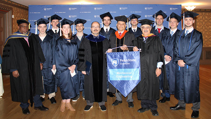 group of 12-15 people wearing graduation regalia