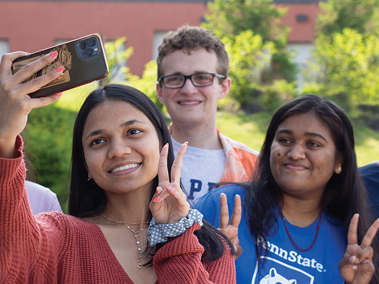 three students smile and pose for a selfie photo