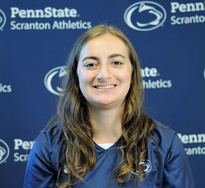 Ashlyn McNally poses for a shot with the PSU Scranton athletics logo as a backdrop