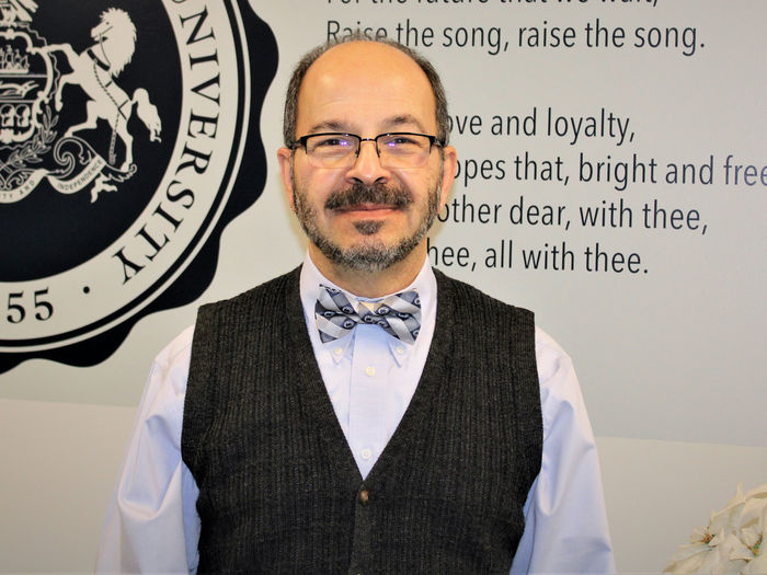 Dr. Wafa standing in front of wall with PSU alma mater graphic displayed on it