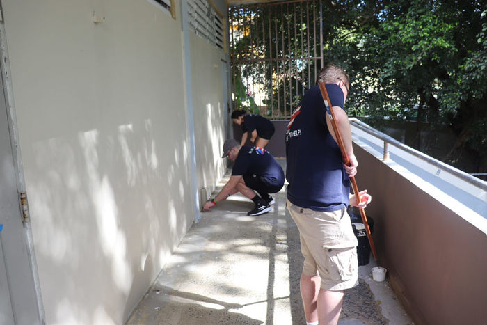 students painting the outside railing and walkway of a building