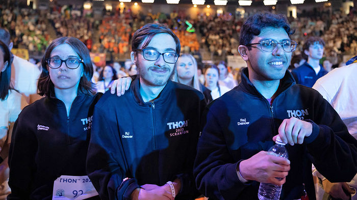 three students in a crowded stadium