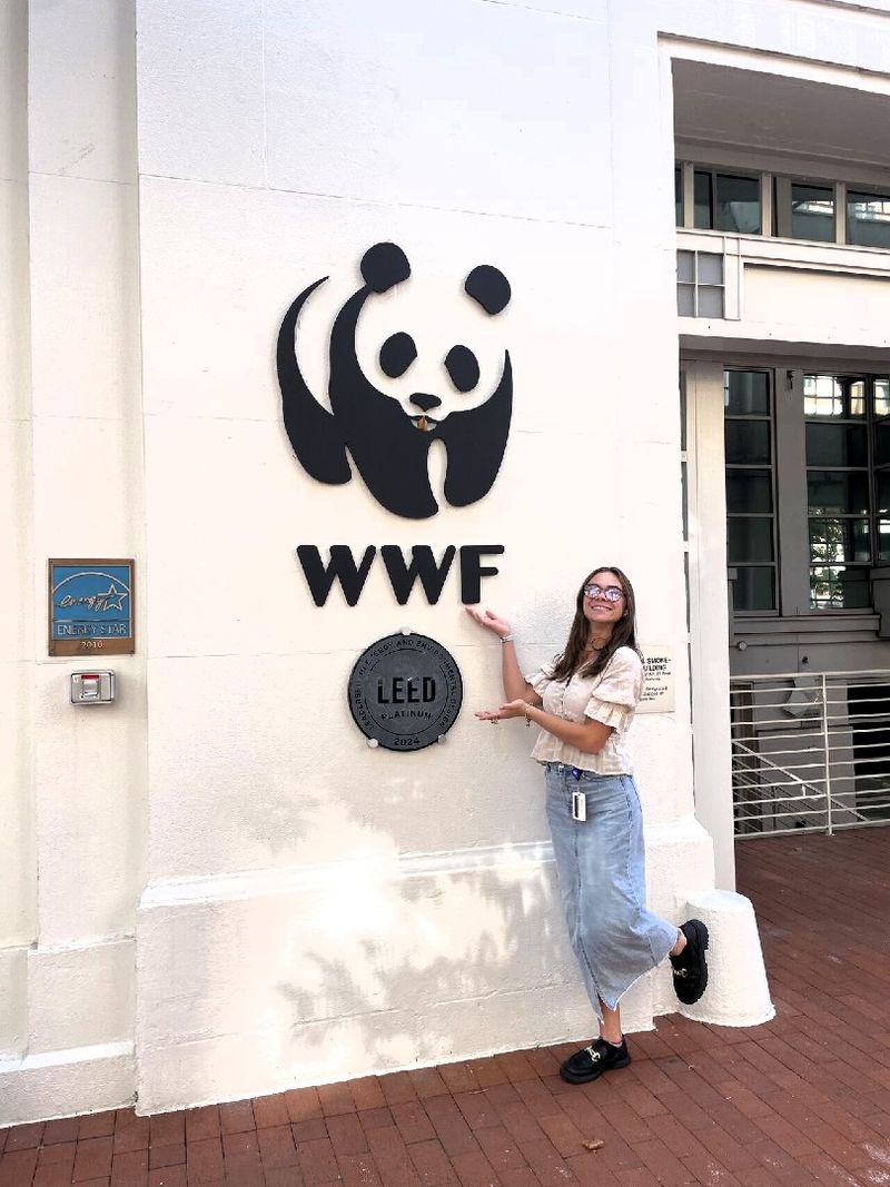 A student stands next to a World Wildlife Fund logo