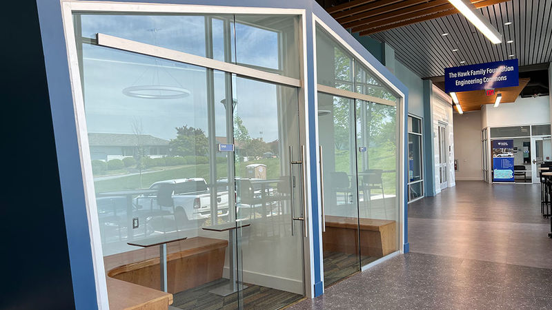 enclosed glass structure  with seating in a hallway of a modern building