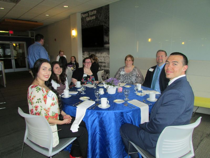 Students seated at table pose for a photo