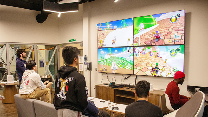 view of group of students playing game on four tv screens