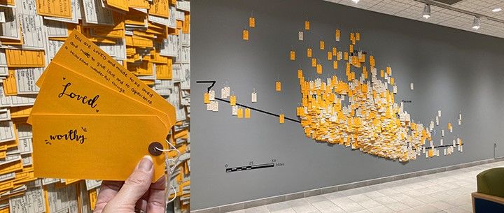 Exhibit of memorial wall of toe tags for Hostile Terrain project