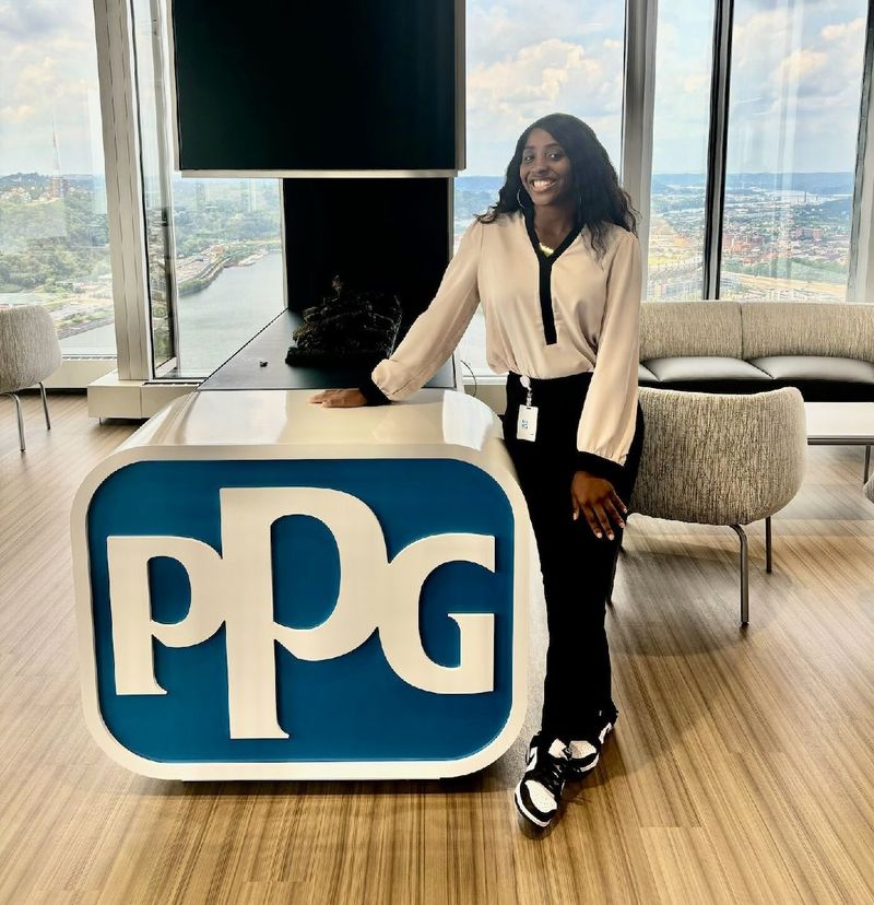 A student stands next to a PPG sign