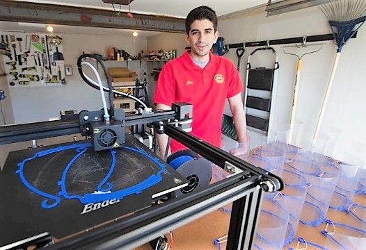 Jim Segona stands next to his 3D printer and some of the face masks he's made with it.