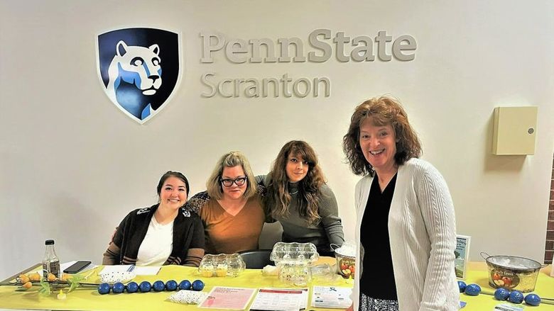 group of staff and students pose for photo at mental health services info table