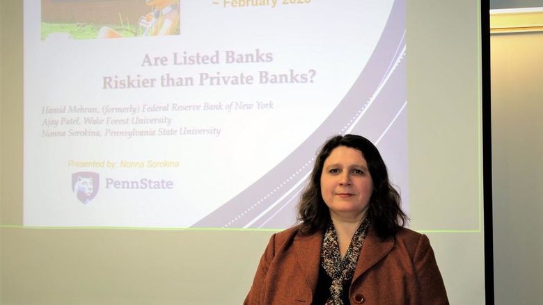 Nonna Sorokina standing in front of a projection screen showing the title of her research project 