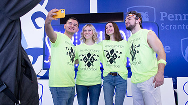 four students in bright yellow scanton THON tee shirts pose for a selfie