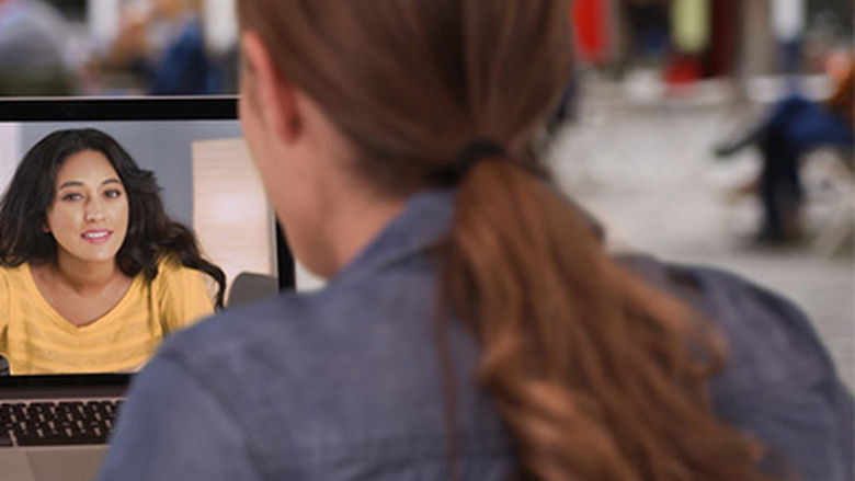 A student interacts with a faculty member on her computer screen.