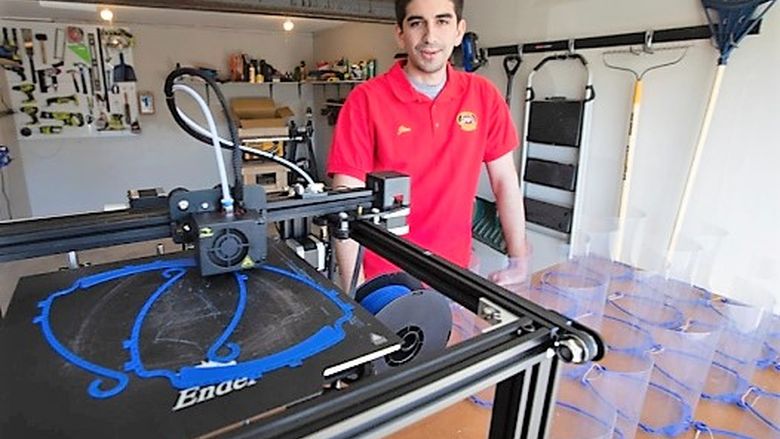 Jim Segona with his 3-D printer and some of the face masks he has produced with it