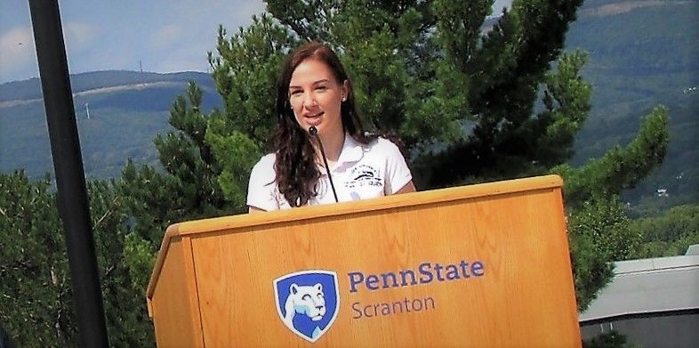 emily scarfo at a podium speaking at a campus event