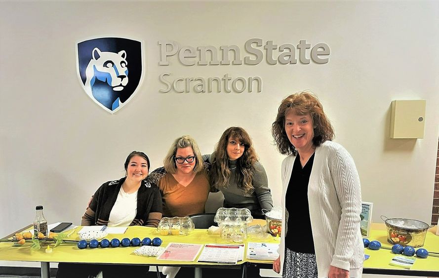 group of staff and students pose for photo at mental health services info table