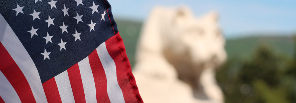 The American Flag with the campus lion shrine in the background